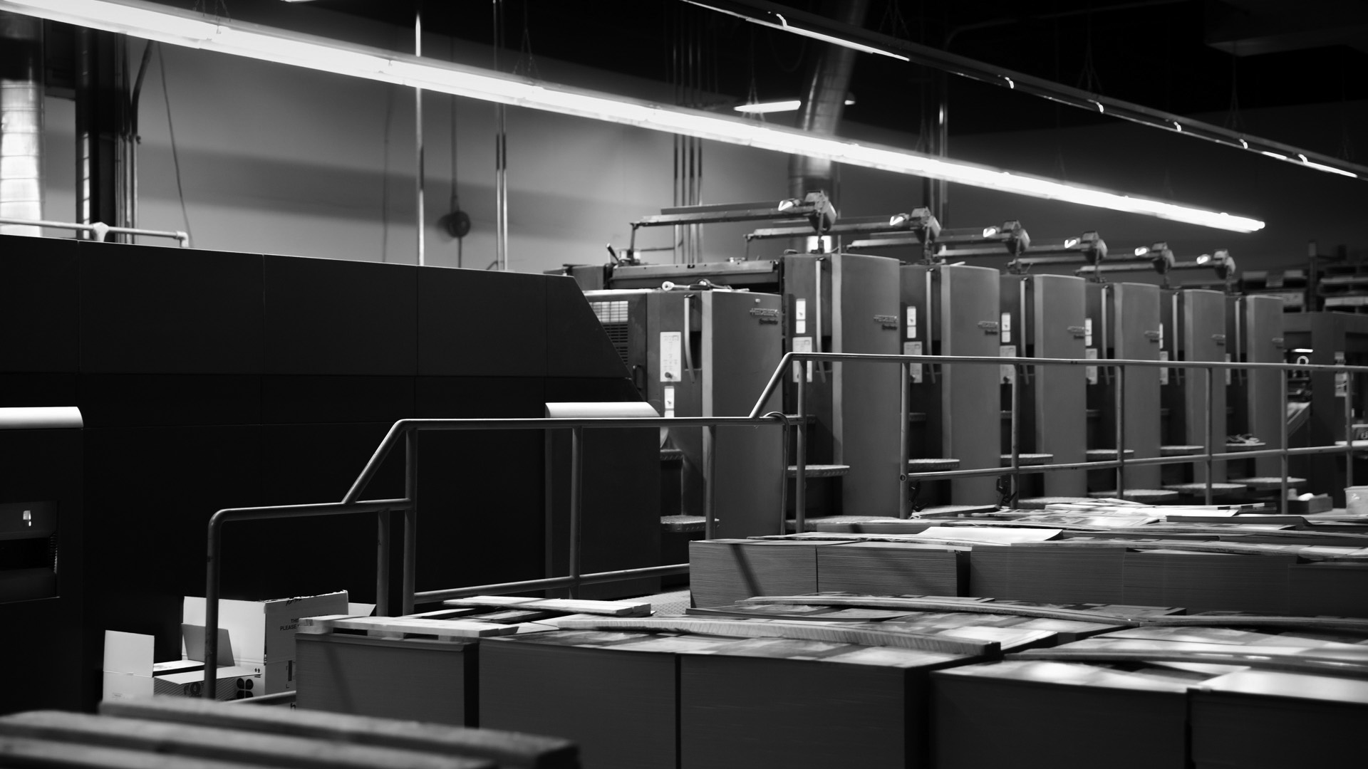 Black and white commercial print production environment featuring professional printing equipment.