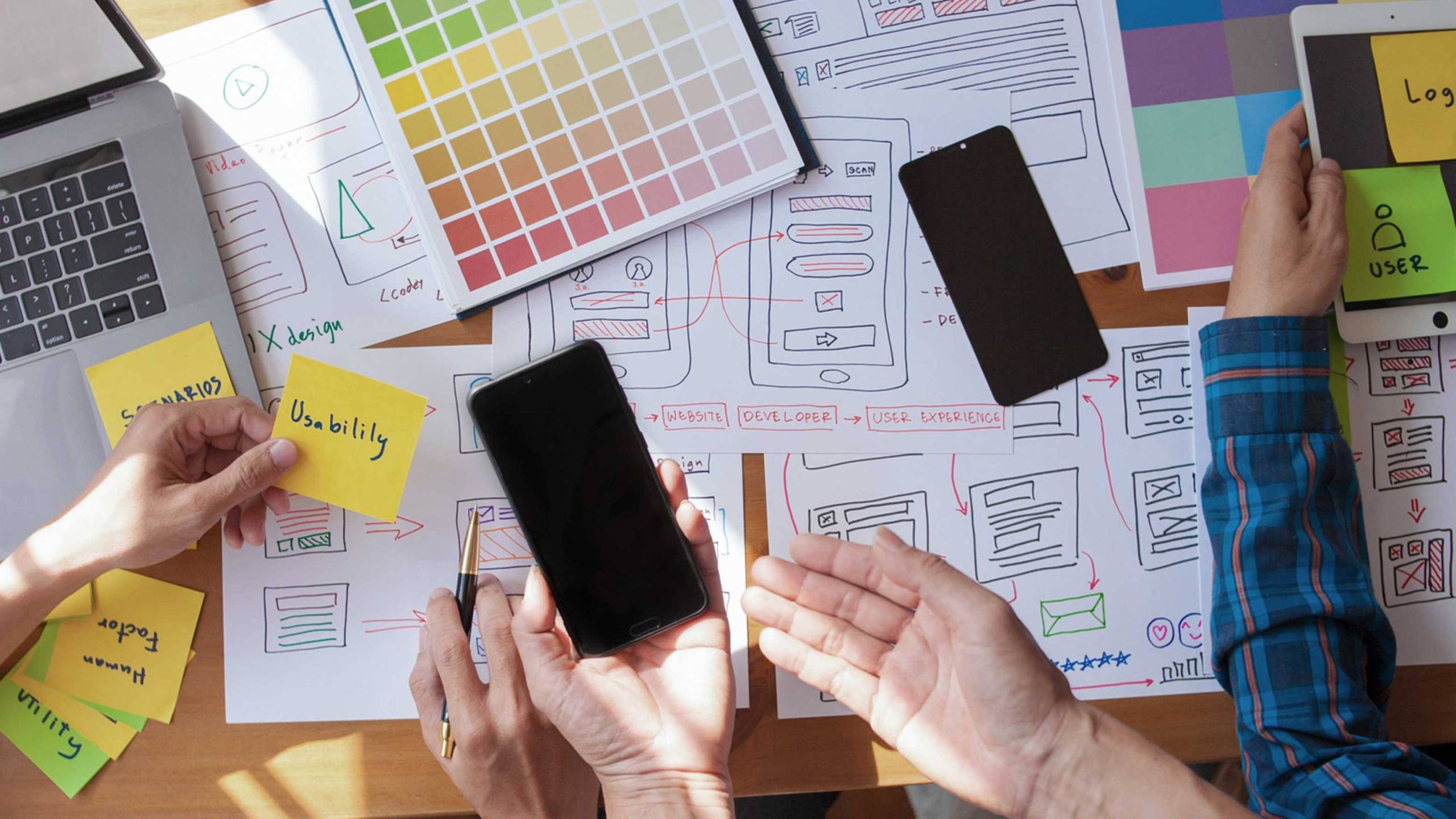 Creative workspace featuring colour samples, devices and design tools used for marketing and brand development.