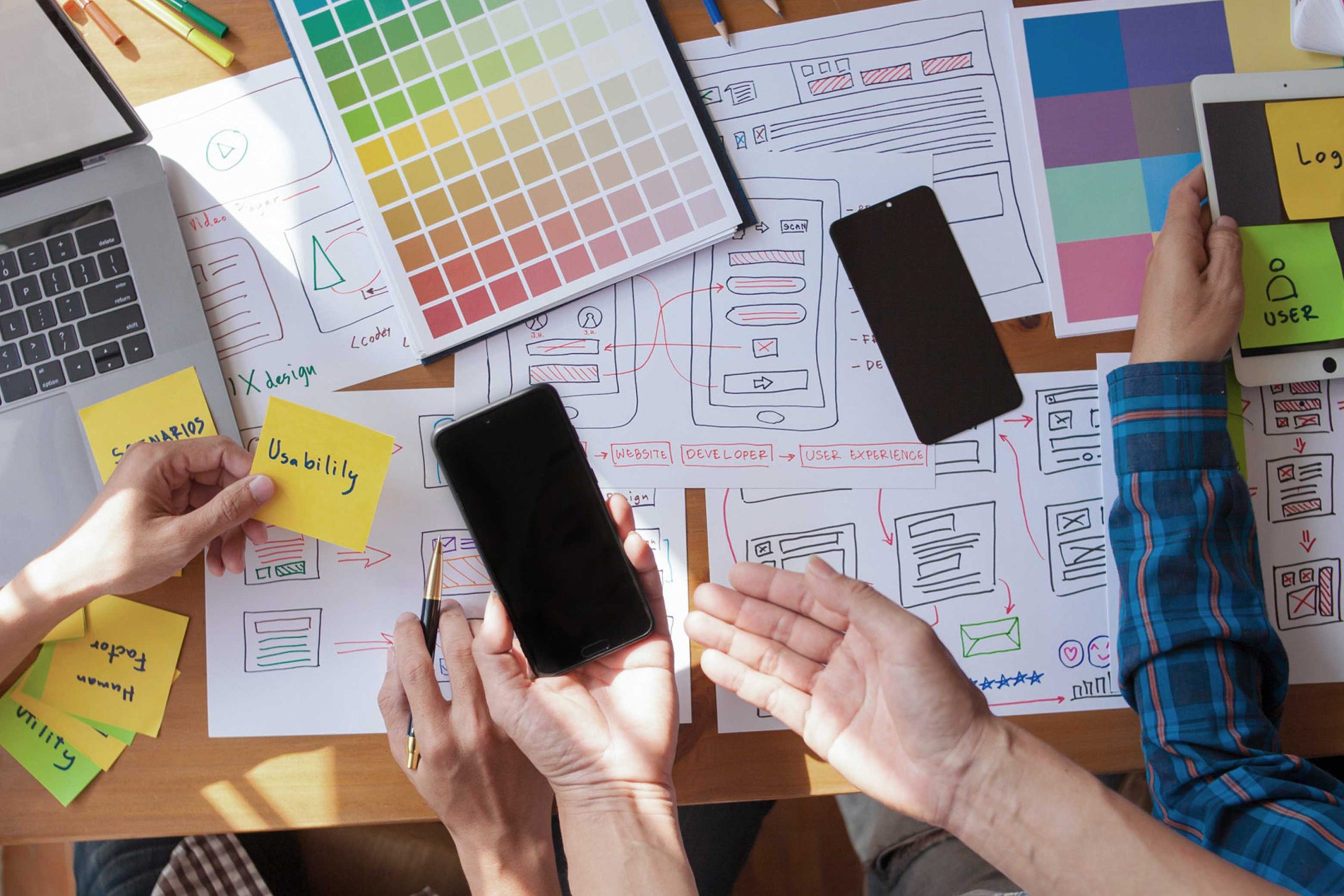 Creative workspace featuring colour samples, devices and design tools used for marketing and brand development.