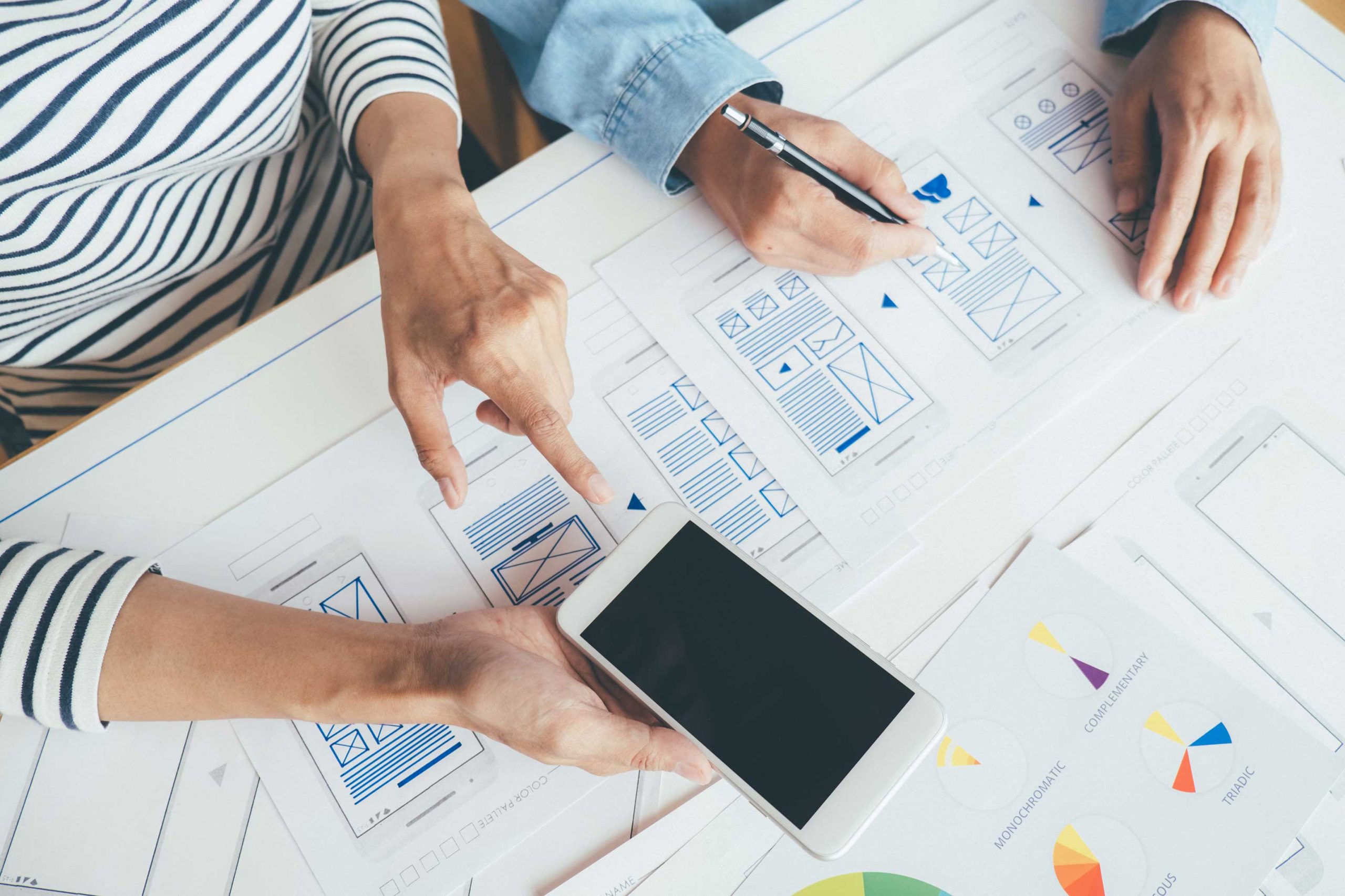 Designer planning a website experience using sketches, layouts and digital design tools.