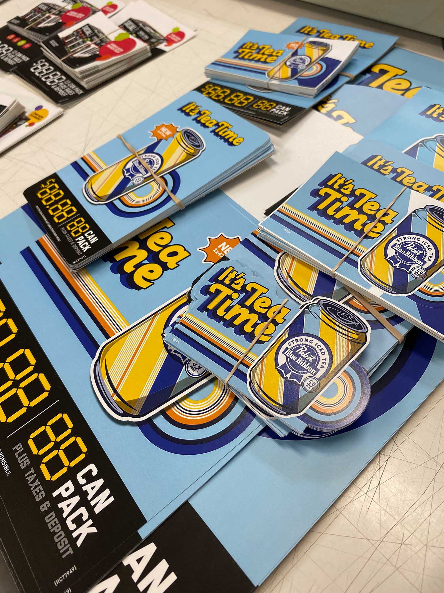 Printed promotional materials arranged during production for a custom retail kitting campaign.