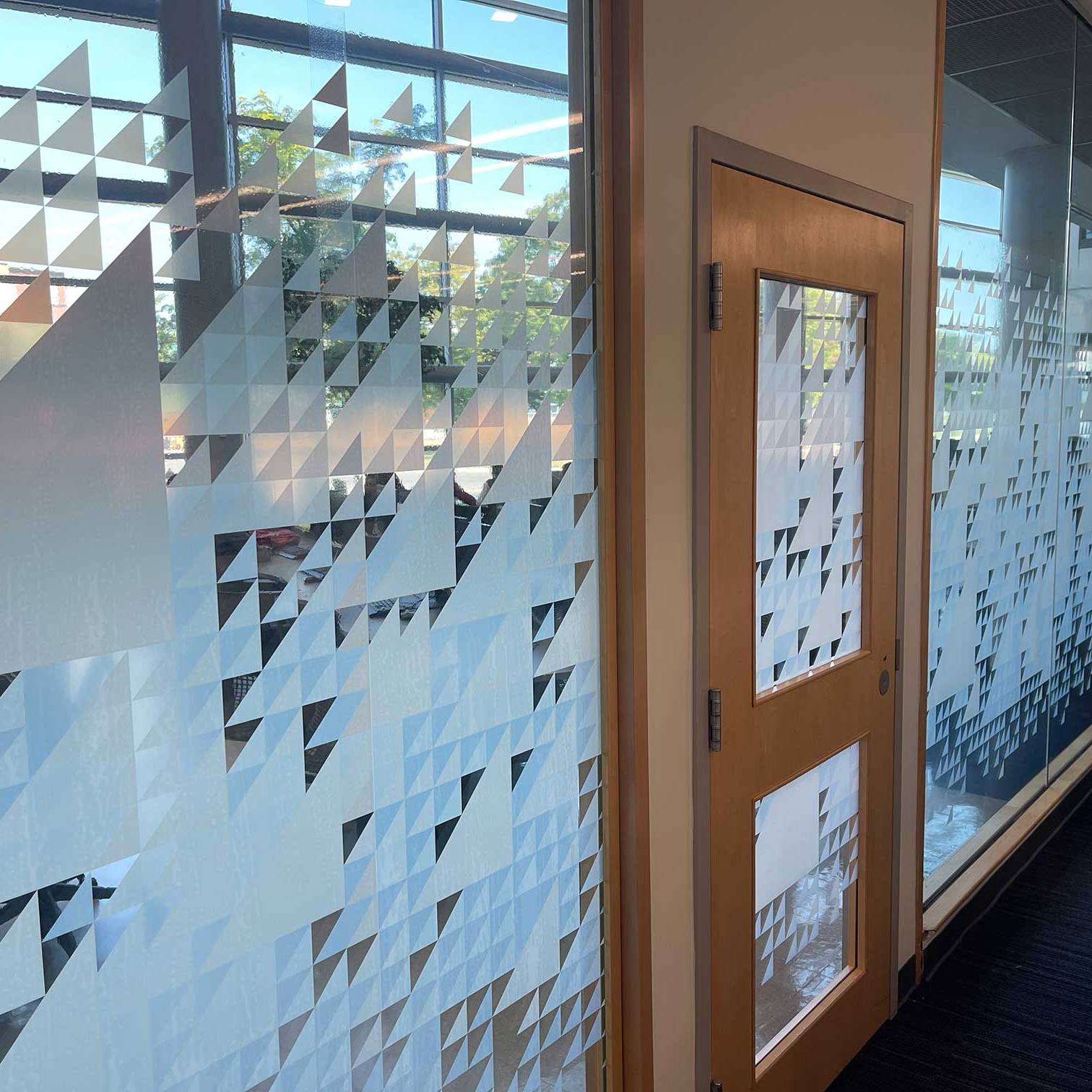 Custom frosted privacy graphics installed across glass office walls and meeting room windows.